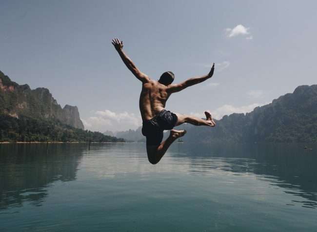 man-jumping-with-joy-by-a-lake-2022-09-16-08-05-00-utc_c